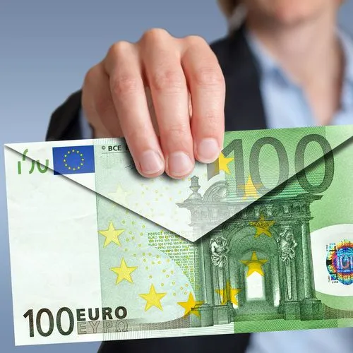 Eine Frau hält einen Briefumschlag in Richtung einer Kamera. Der Briefumschlag wurde aus einem großen 100-Euro-Schein gefaltet.