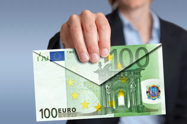 Eine Frau hält einen Briefumschlag in Richtung einer Kamera. Der Briefumschlag wurde aus einem großen 100-Euro-Schein gefaltet.