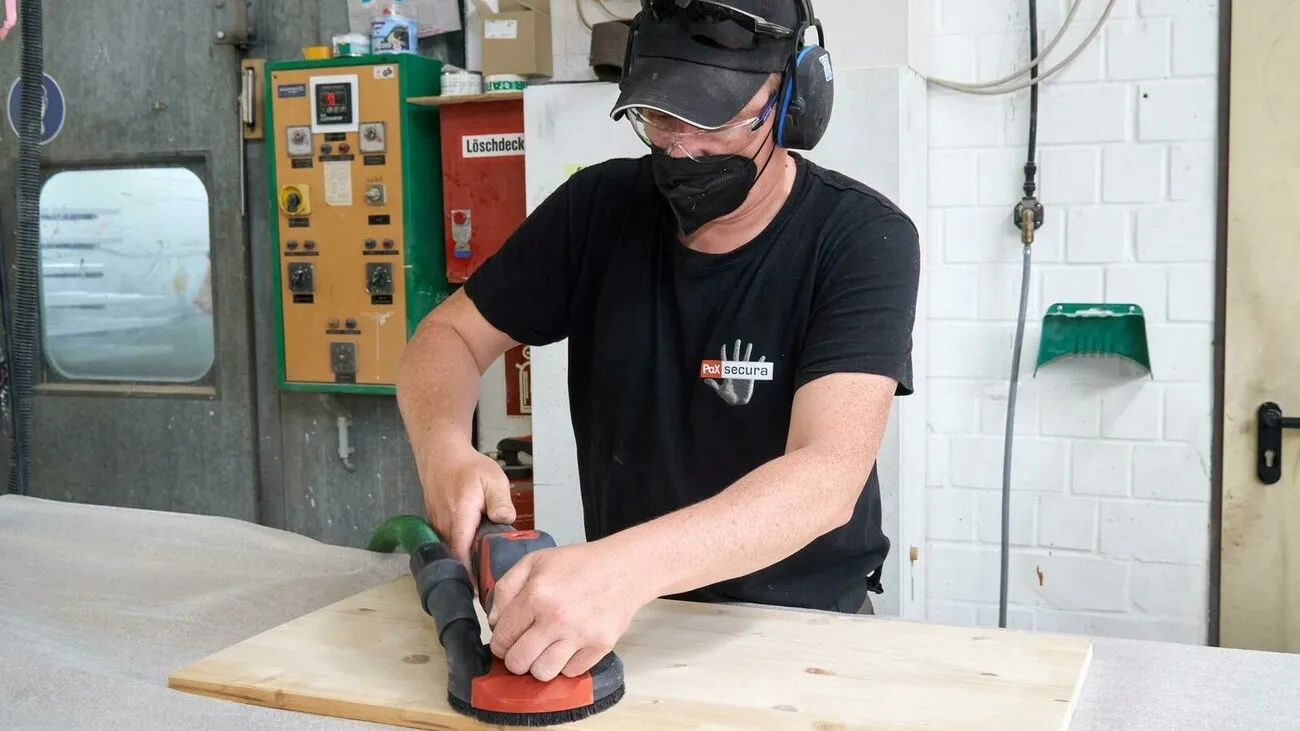 Der Tester bedient die Akku-Supraflex an einer Holzplatte und trägt dabei einen Gesichtsschutz.