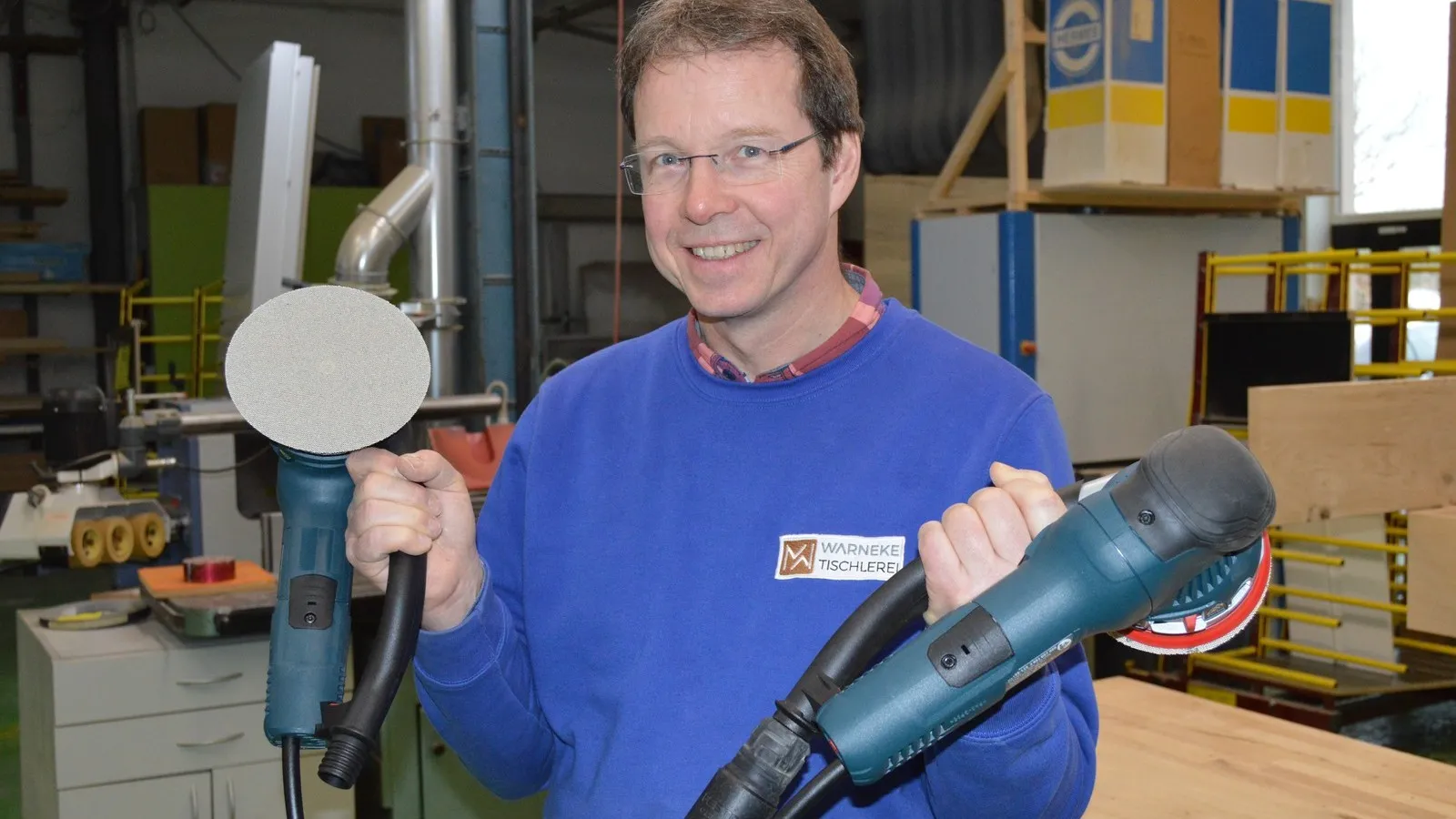 Matthias Warneke hält die Bosch Exzenterschleifer in jeweils einer Hand.