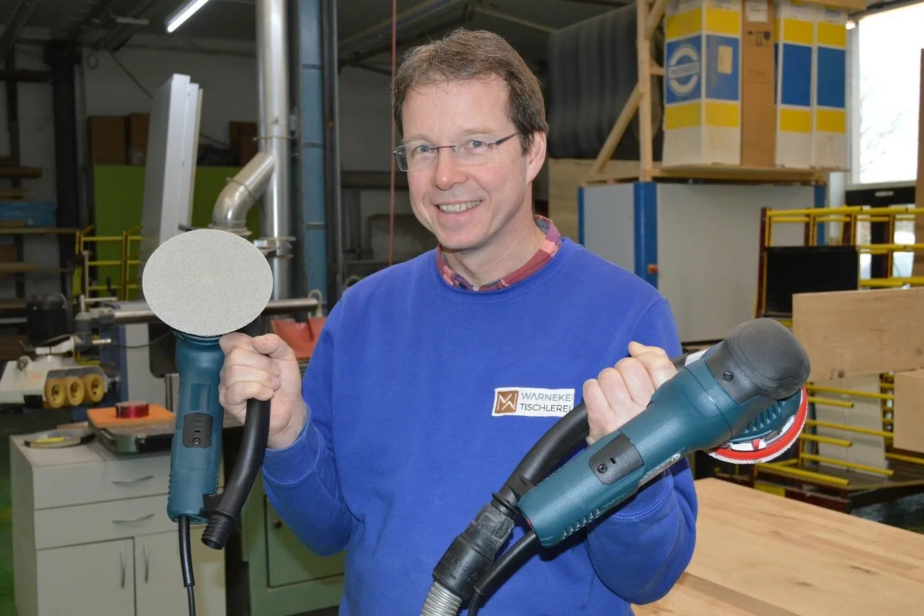 Matthias Warneke hält die Bosch Exzenterschleifer in jeweils einer Hand.