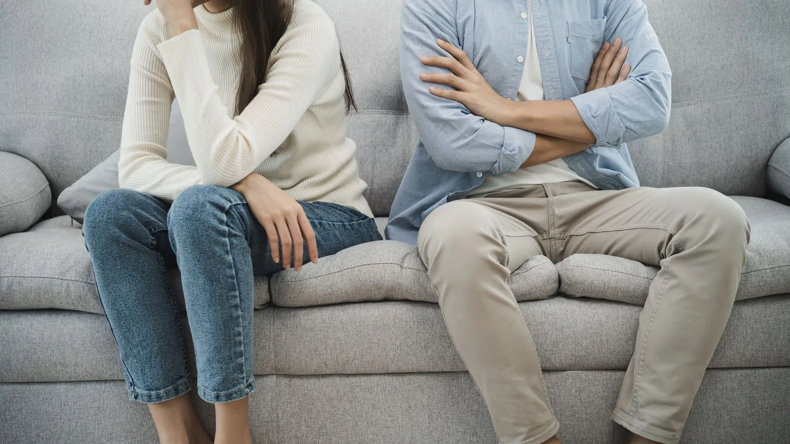 Paar sitzt zusammen auf dem Sofa, die Körper von Mann und Frau sind aber voneinander abgewand.