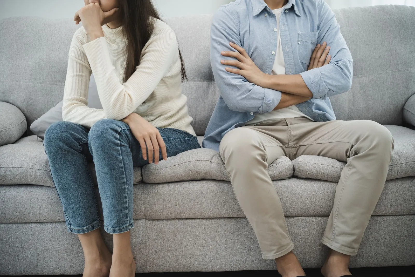 Paar sitzt zusammen auf dem Sofa, die Körper von Mann und Frau sind aber voneinander abgewand.