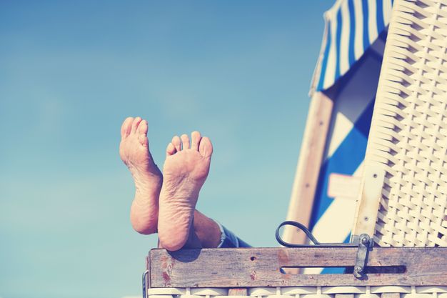 Jemand liegt im Strandkorb und legt die Füße auf die Lehne.