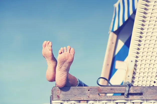 Jemand liegt im Strandkorb und legt die Füße auf die Lehne.