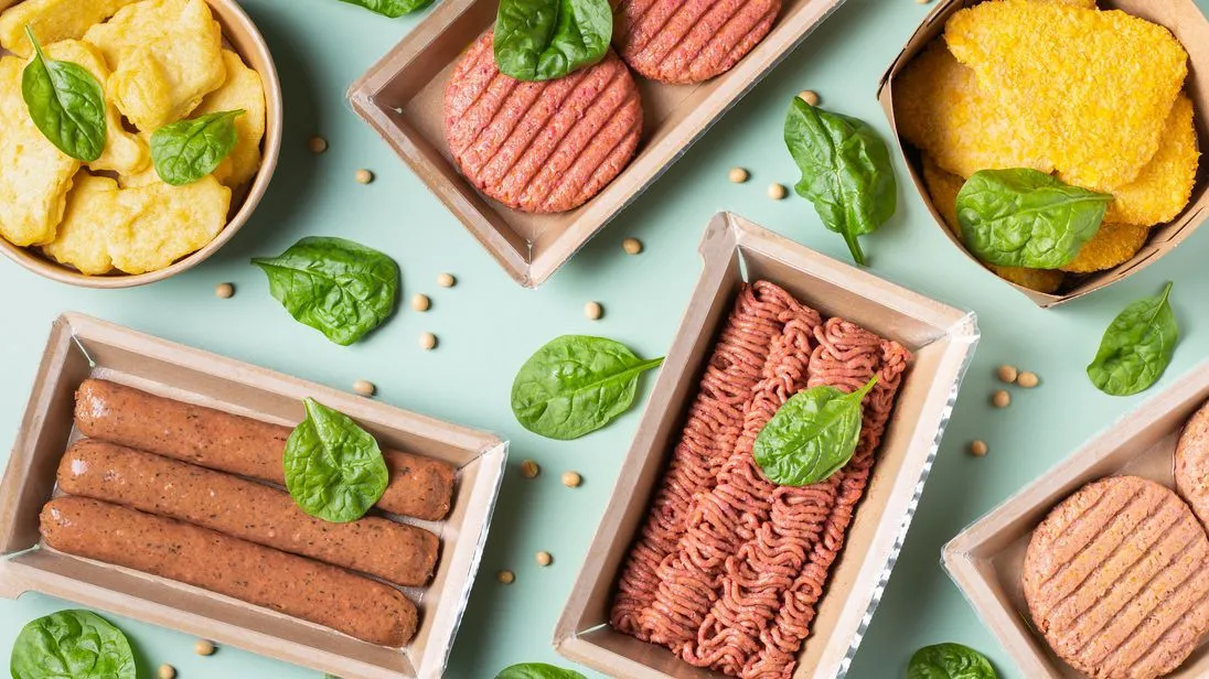 Eine Auswahl an Veggie-Produkten wie Veggie-Hackfleisch und Veggie-Burger sind auf einem Tisch angerichtet.