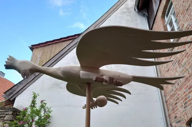 Ein hölzerner Schützenvogel mit Zepter und Reichsapfel auf einer Stange.