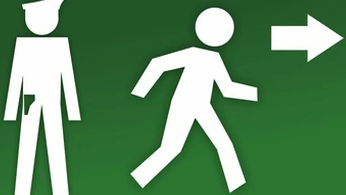 Ein grünes Schild mit weißen Figuren, das zeigt wie eine Person von einem Zollbeamten flüchtet.